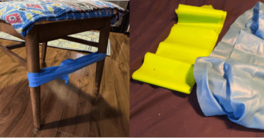 A blue band tied around the legs of a chair, a yellow and a gray band flat on the floor.