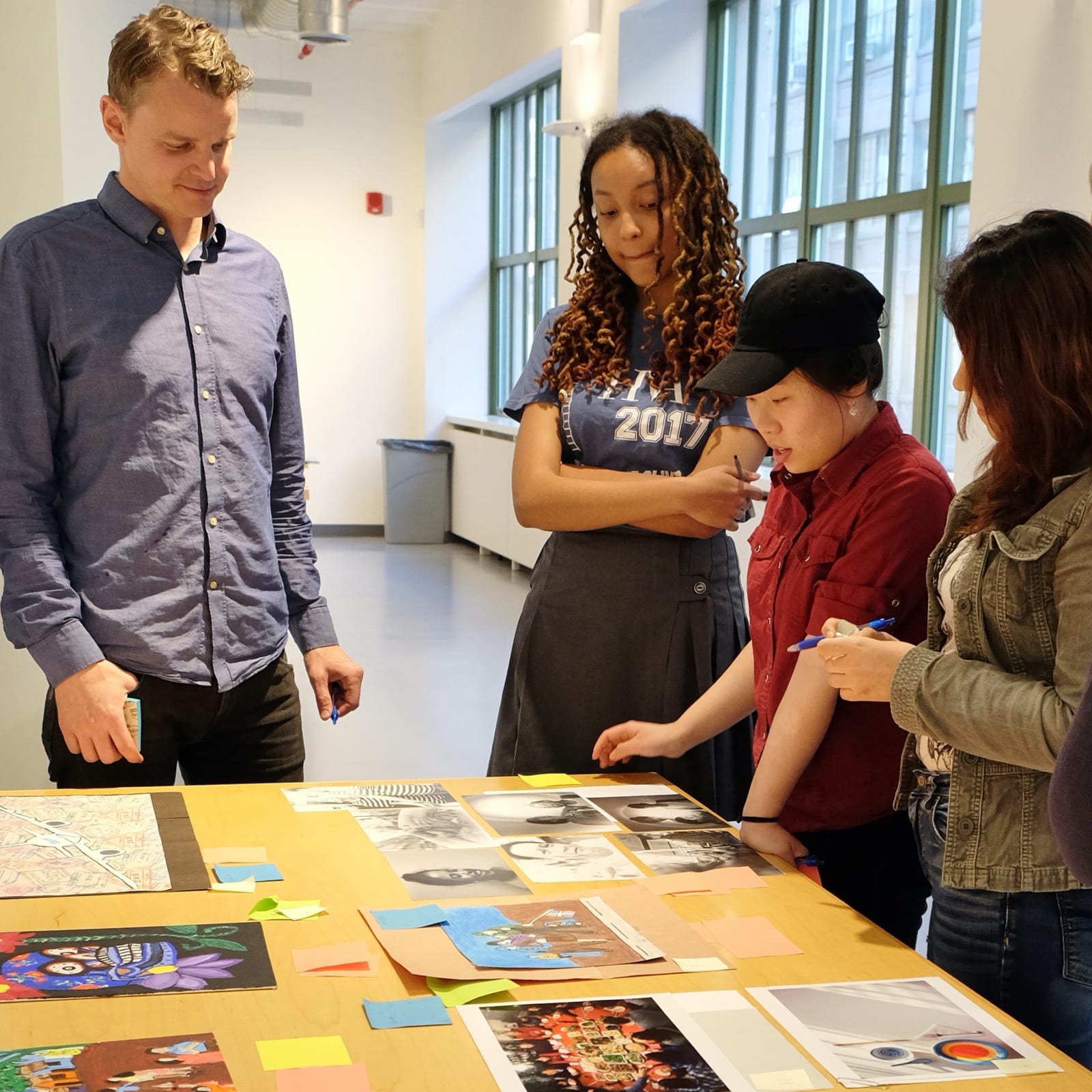Teaching artist looks at visual artwork with teenage students